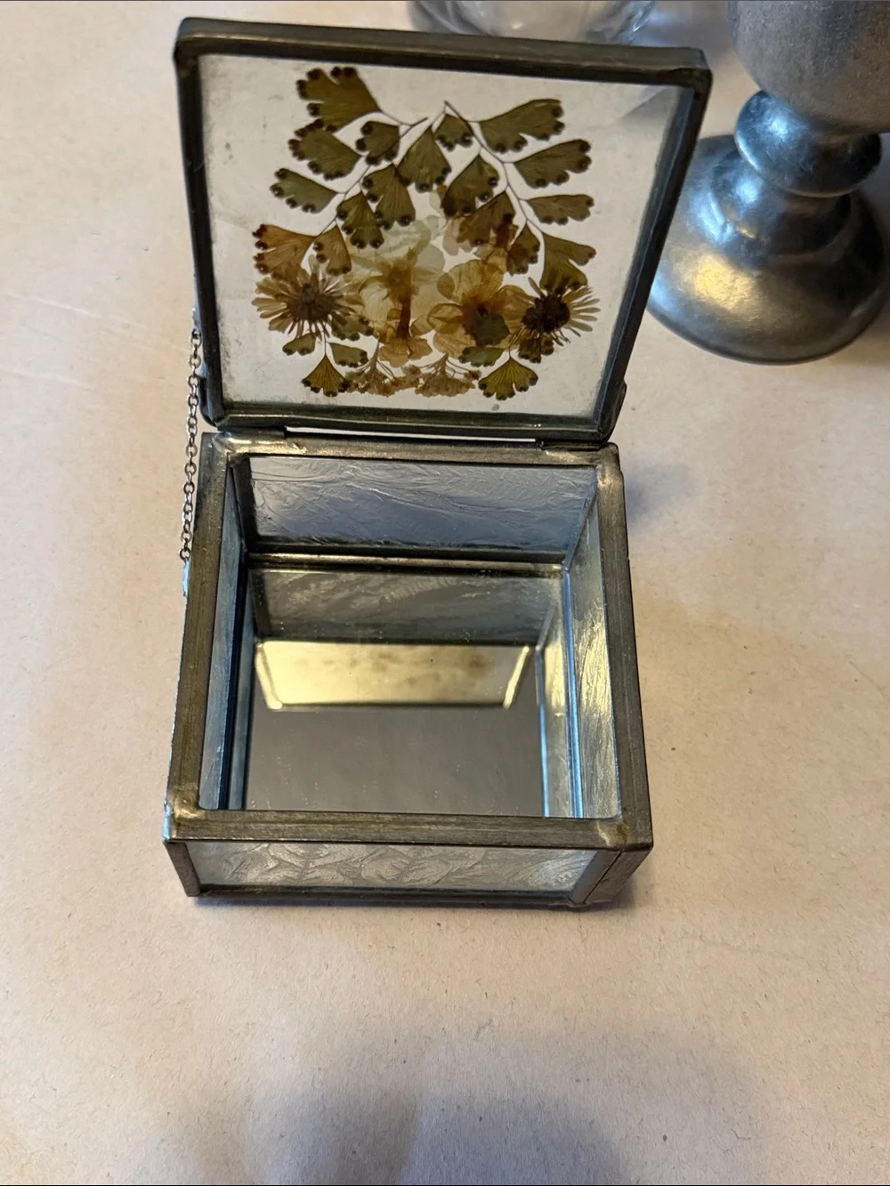 Vintage trinket box with metal edges and dried flowers on top. Mirror bottom.